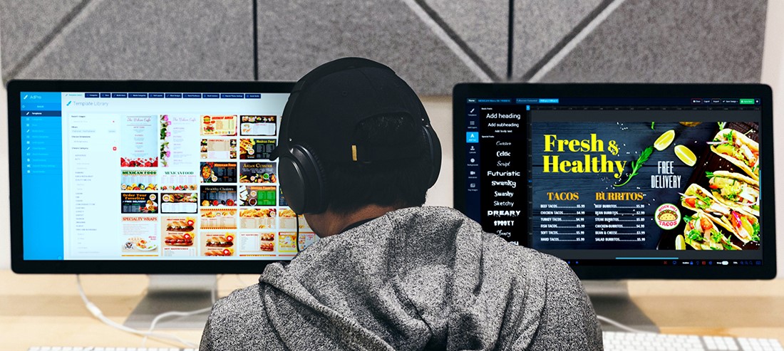 man designing digital menu boards at computer