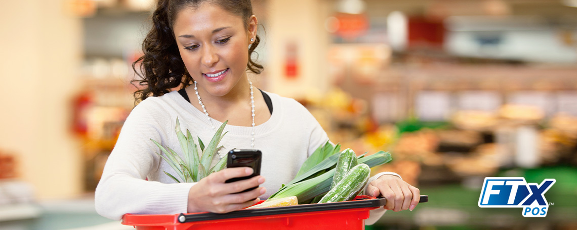 a woman shopping at a grocery store checking her grocery loyalty app on her smartphone