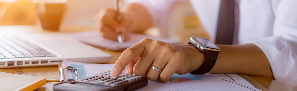 Person calculating finances with a calculator and documents 