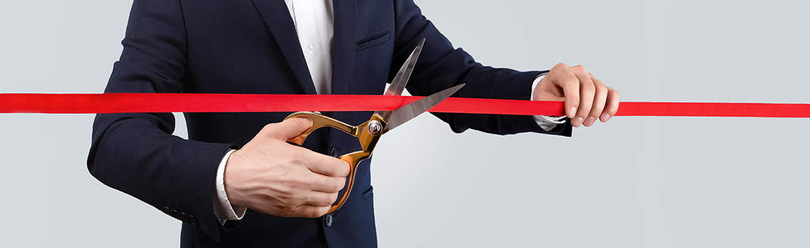 Businessman cutting a red ribbon at a grand opening event